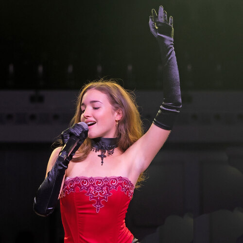 Eine Sängerin singt auf der Bühne in rotem Kleid