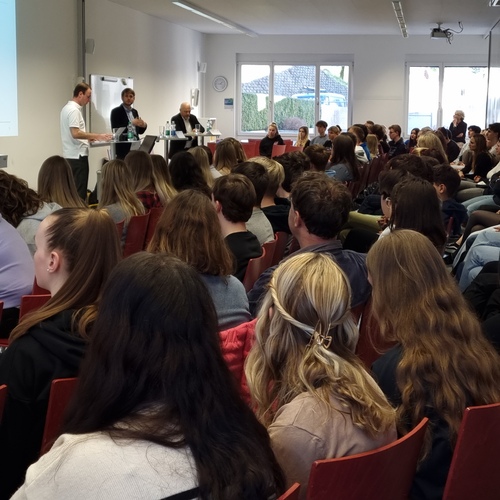 Die Lernenden hören bei einem Politikpodium in der Aula aufmerksam zu
