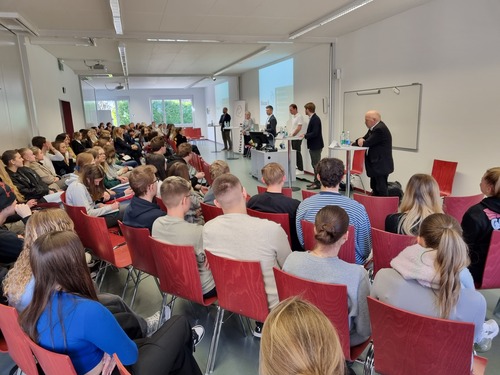 Politikerinnen und Politiker nehmen an einer Podiumsdiskussion vor Lernenden neutral Stellung zu verschiedenen politischen Themen